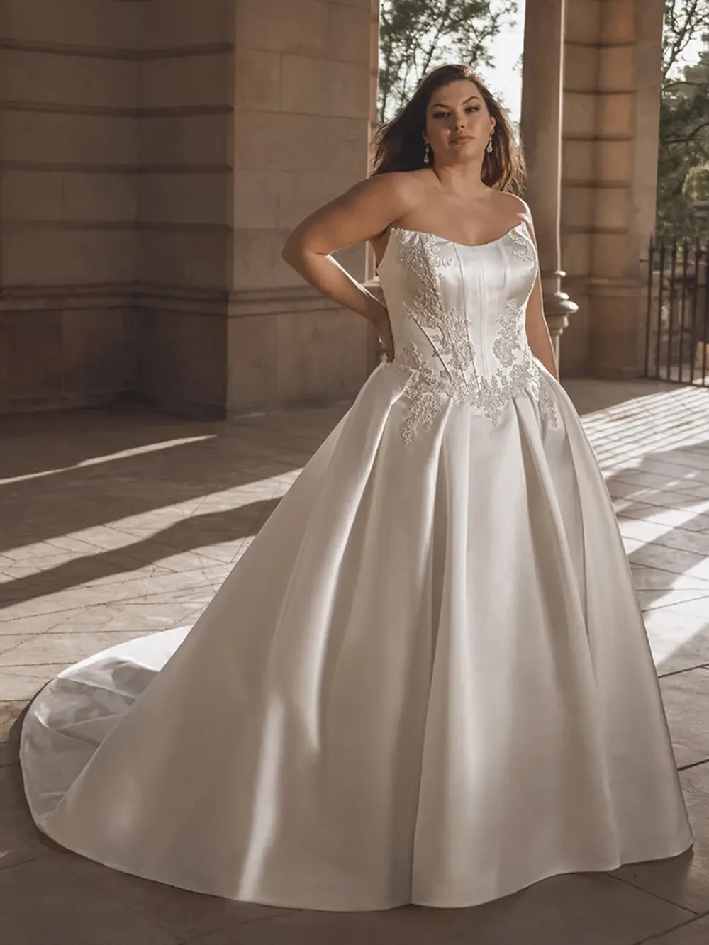 model is wearing a plus size strapless ball gown