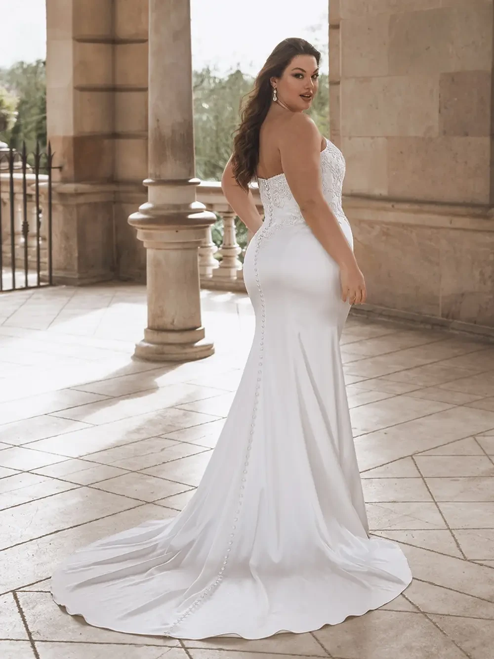 model is wearing a strapless fit and flare plus size bridal gown