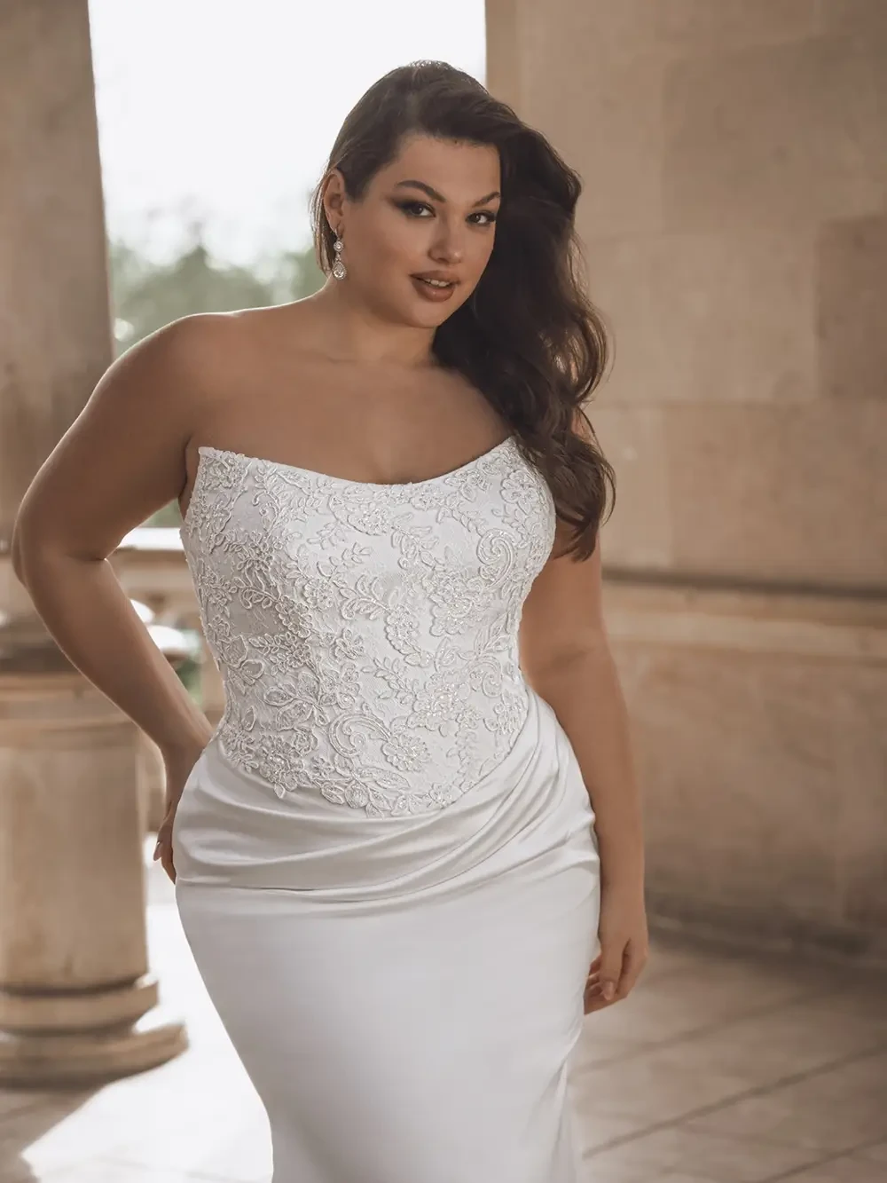 model is wearing a strapless fit and flare plus size bridal gown
