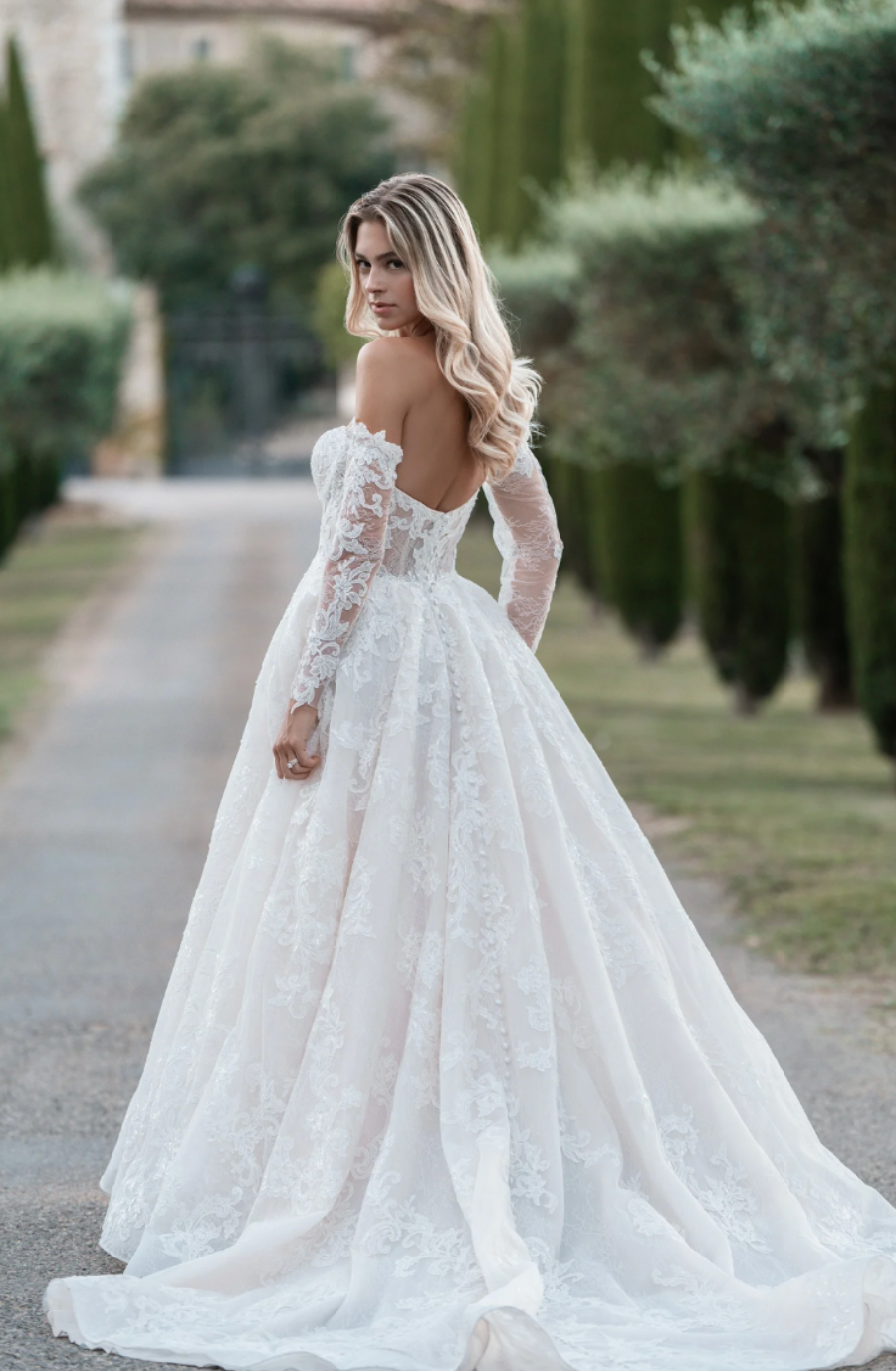 model is wearing an off the shoulder long sleeve ball gown