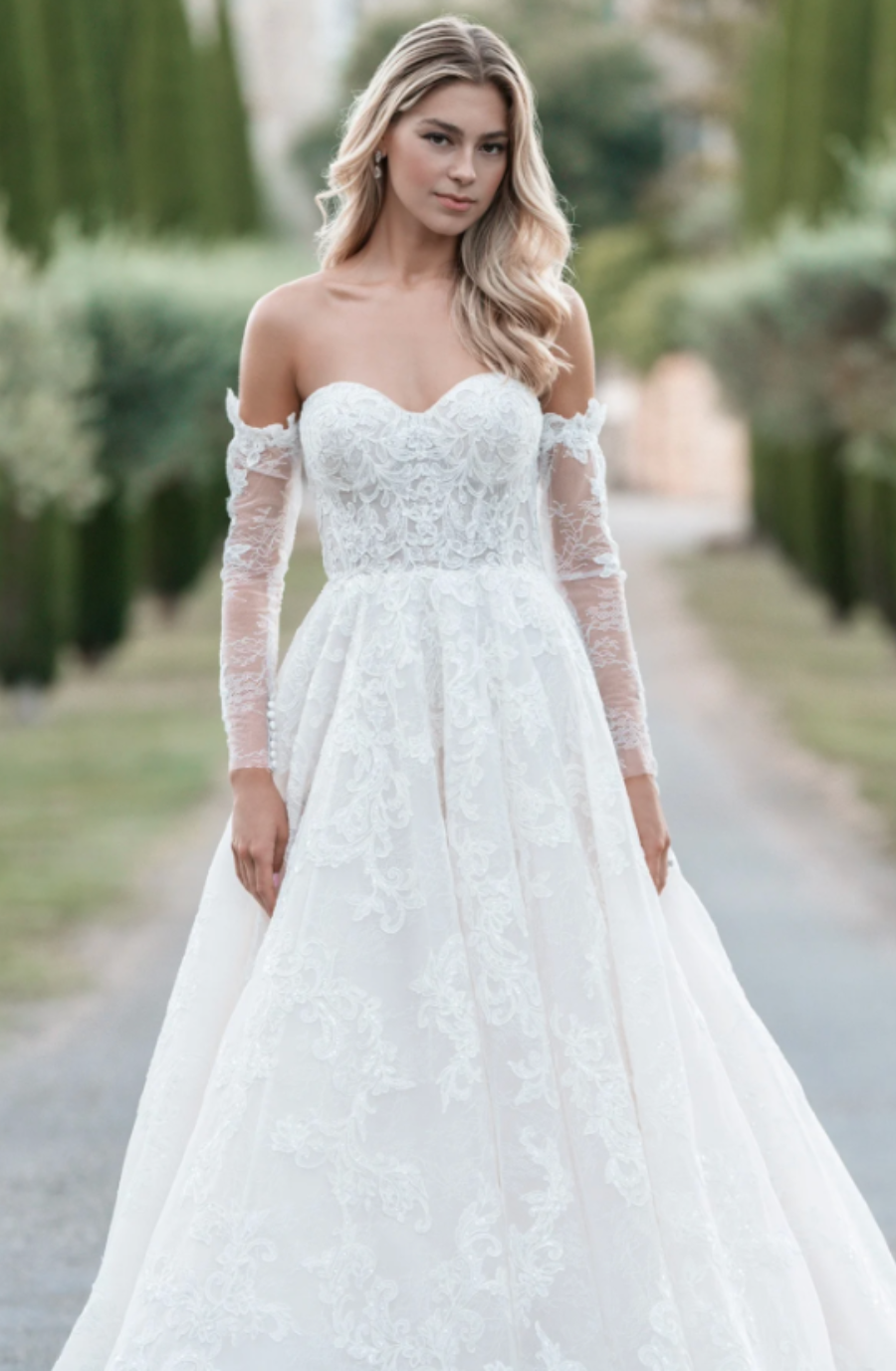 model is wearing an off the shoulder long sleeve ball gown