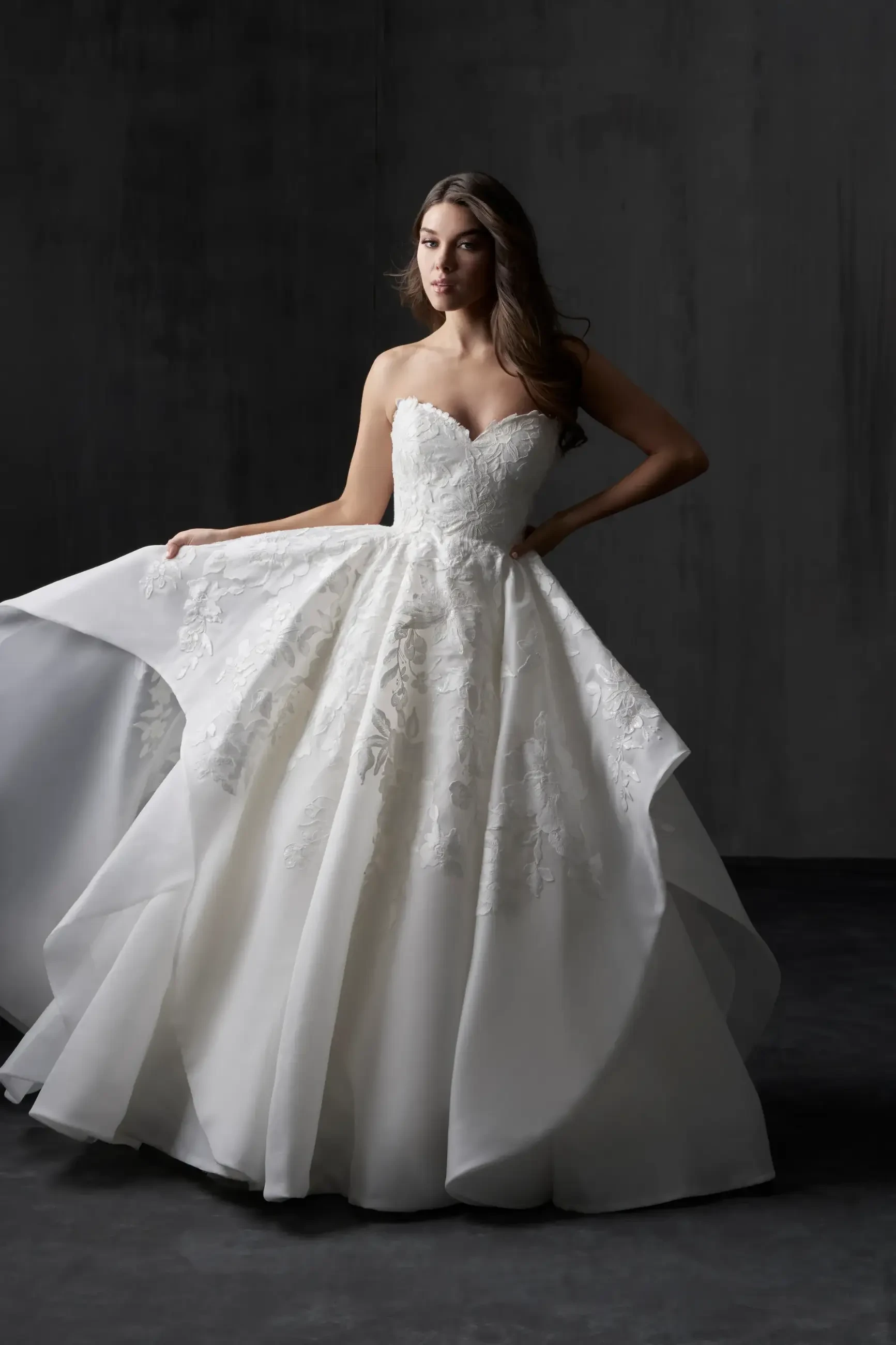 model is wearing a strapless organza ball gown wedding dress