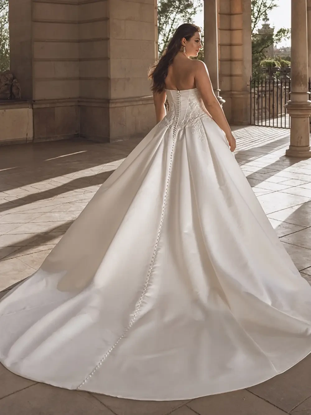 model is wearing a plus size strapless ball gown