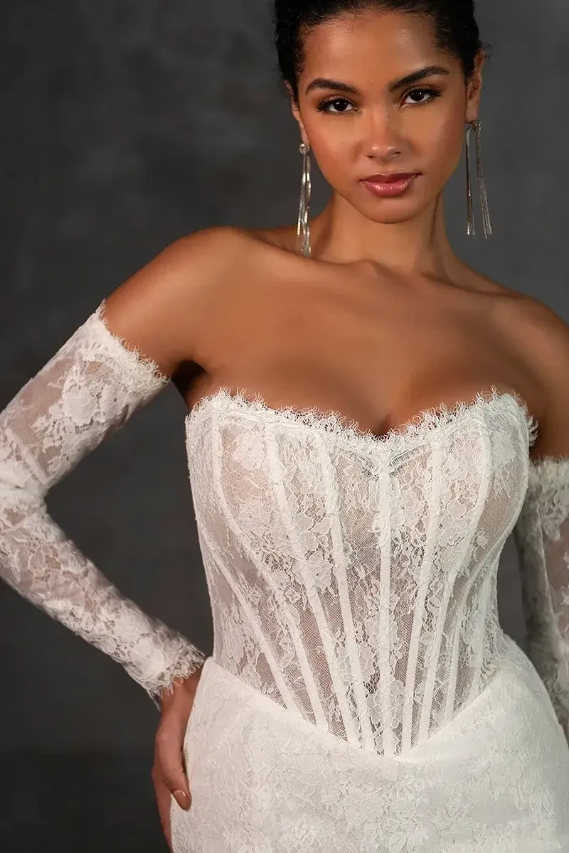 model is wearing a lace strapless fit and flare wedding dress with detachable long sleeves